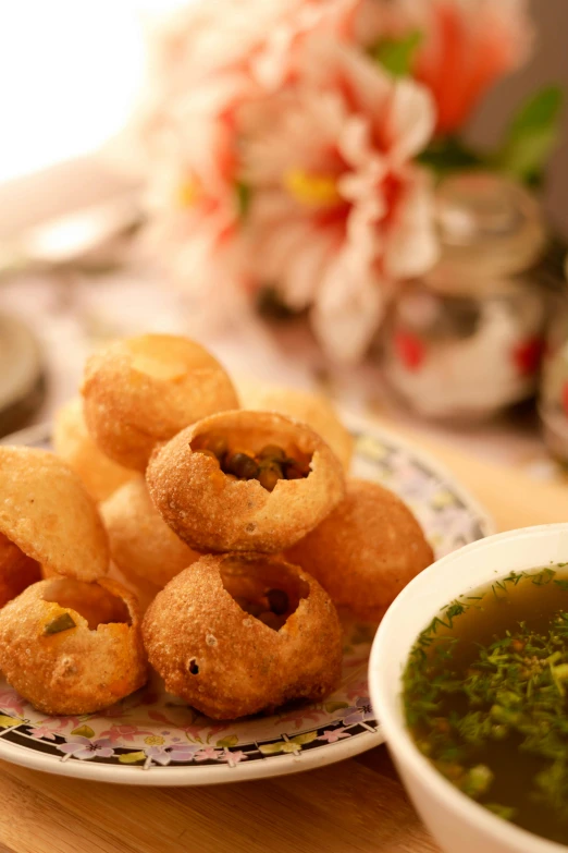 small bread rings sit on a plate next to broccoli and dipping sauce