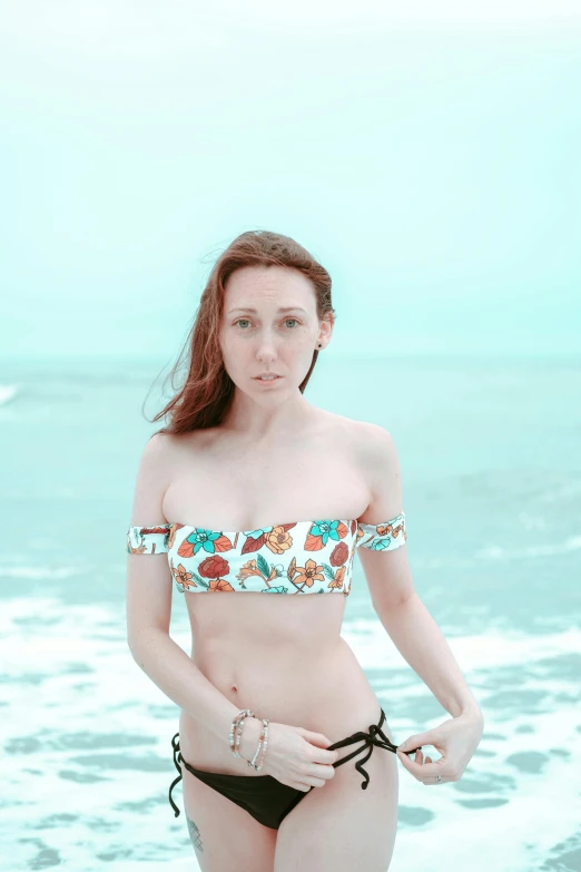 a girl in a bikini standing on the beach