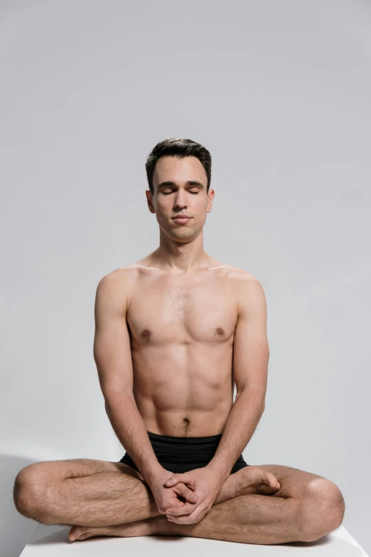 shirtless man sitting on table with head in hand and eyes closed