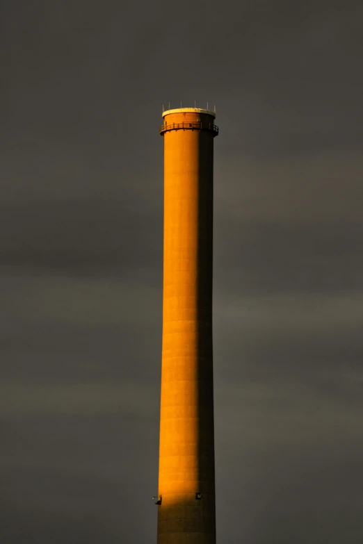 a tall yellow tower standing in front of a cloudy sky