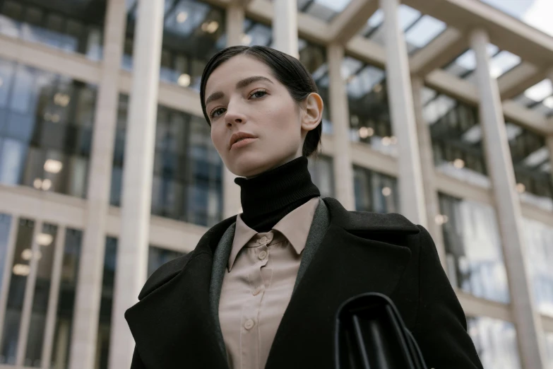 a woman stands in front of a building with lots of glass windows