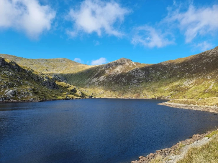 a large mountain lake surrounded by grassy hills