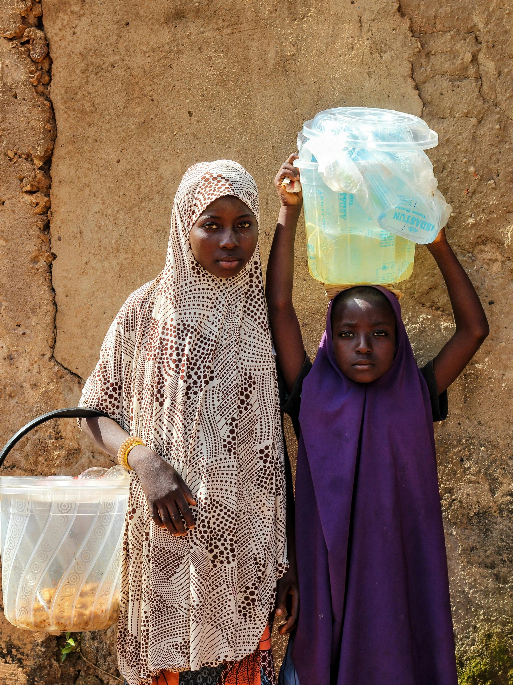 two women standing next to each other holding trash cans