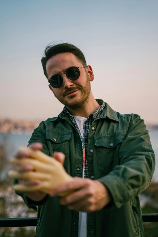 man in sunglasses holding up an object with water in the background