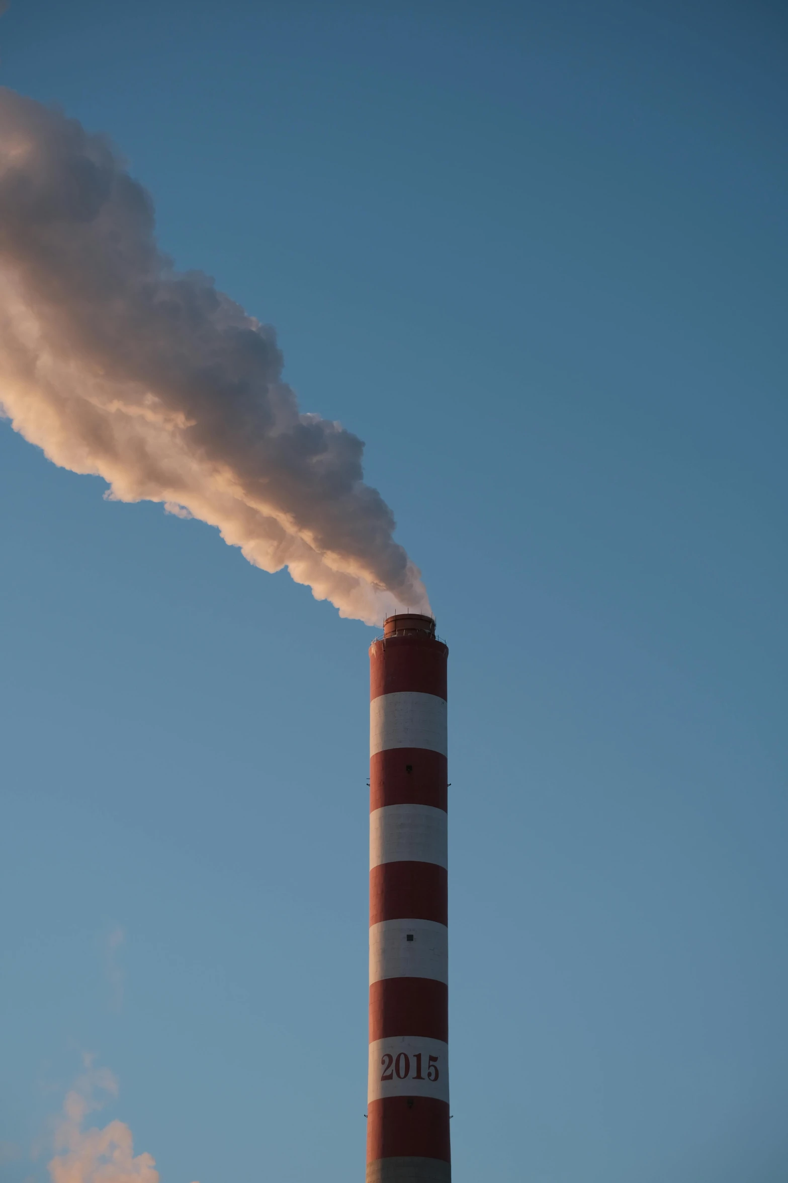 an orange and white smokestack emits from a red and white chimney