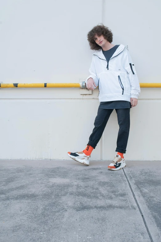 young man leaning against the wall with his arms crossed