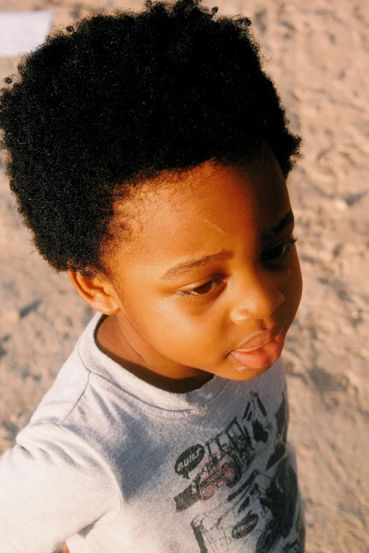 a young child standing in the sand, holding onto a banana