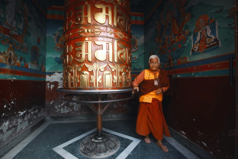 monk standing in front of decoratively painted pillar