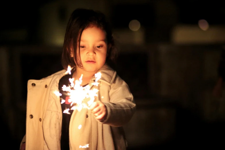 a little girl lighting a sparkler in the dark