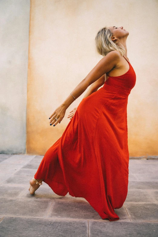 a woman in a red dress dancing in the street
