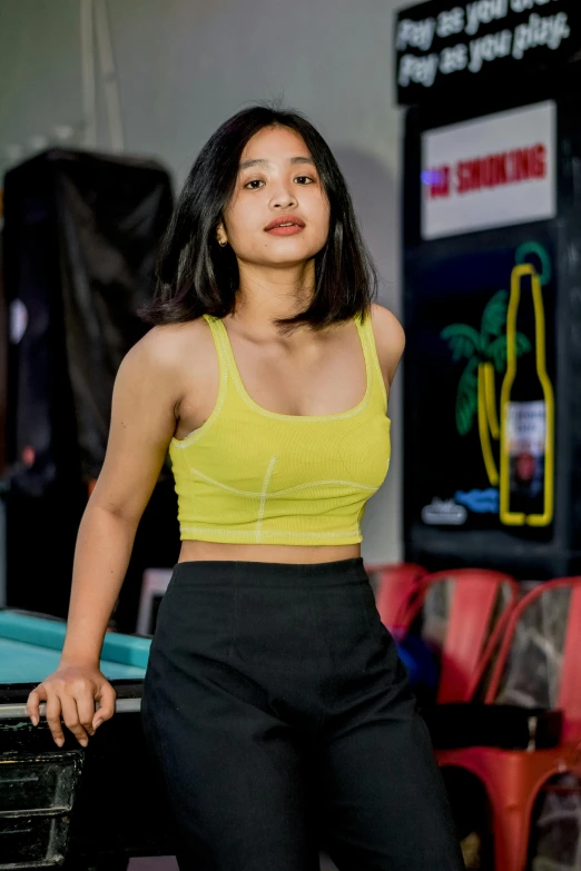 a woman with dark hair wearing a yellow top in a gym