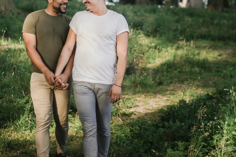 a couple of men holding hands and walking through the woods