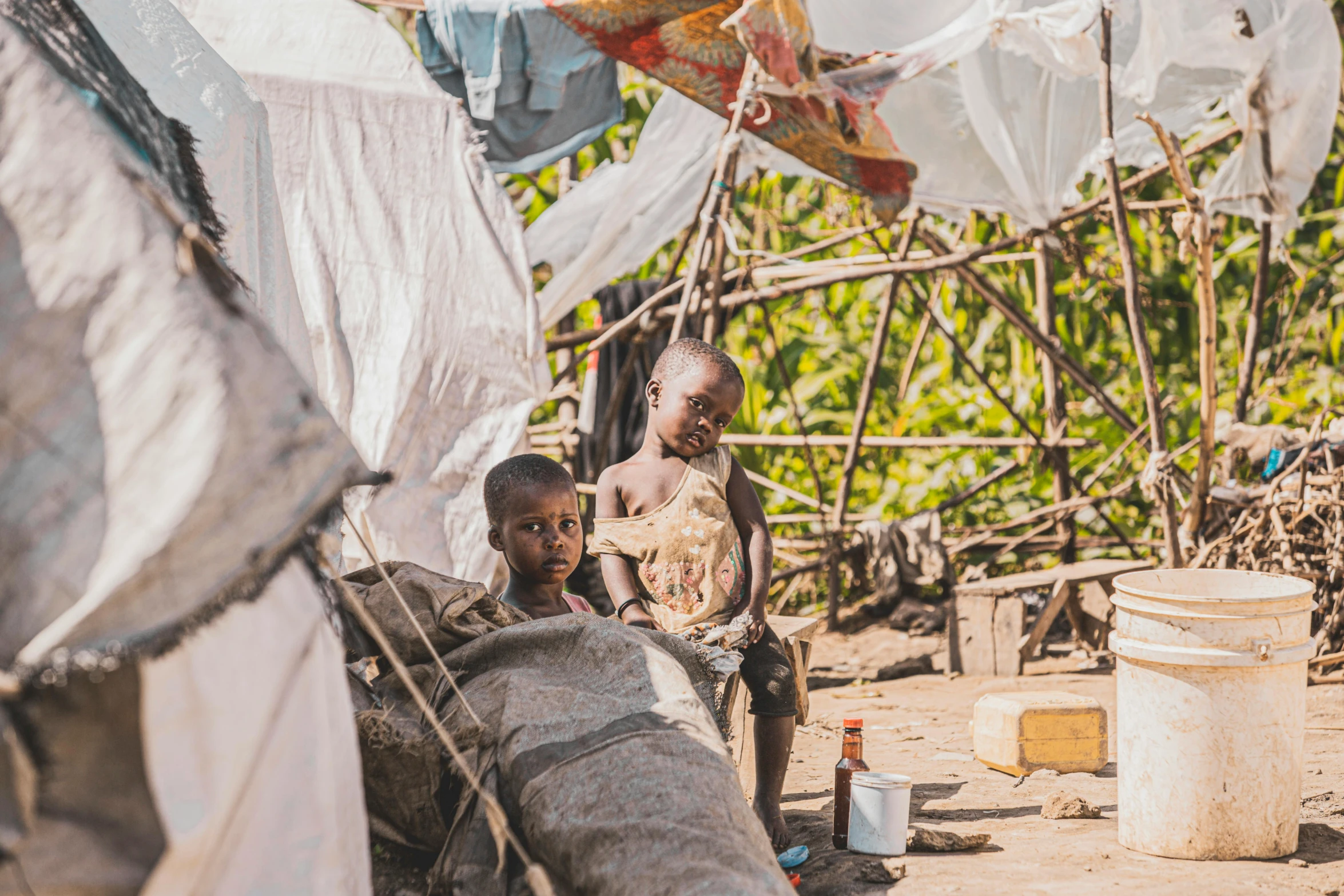 three people stand by their tents with a baby inside