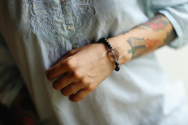 a man with a wrist tattoo and armband that has a small rock in it