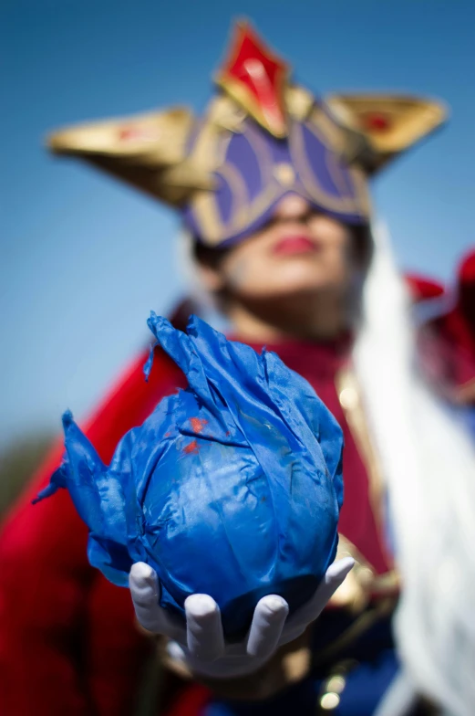 person dressed in costume with face paint holding a plastic ball