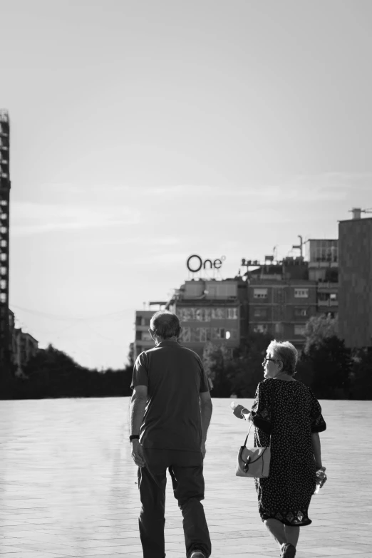 a couple walking down a sidewalk in the evening