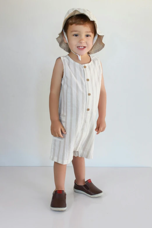 a little girl wearing a white striped dress with a bonnet