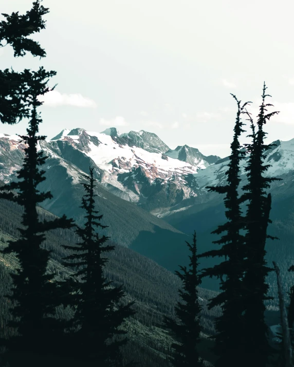 view from the top of a steep mountain, with snow covered mountains in the distance