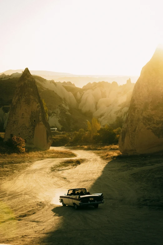 an old car is parked on the side of a dirt road