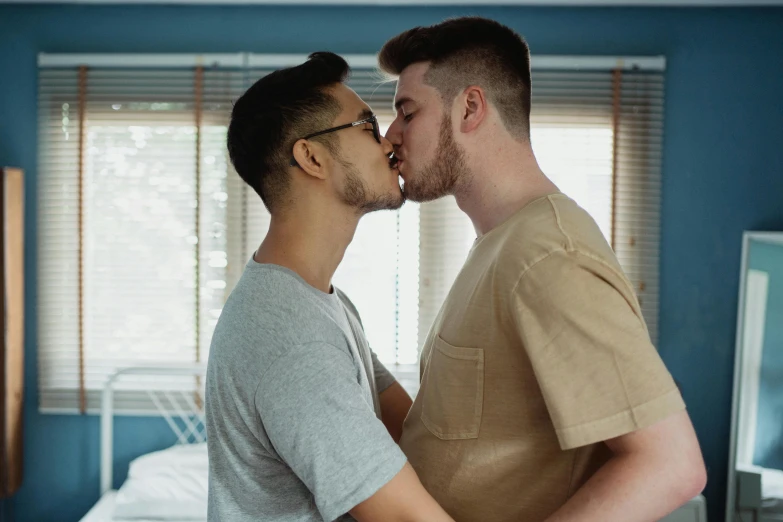 two males are kissing each other in the bed
