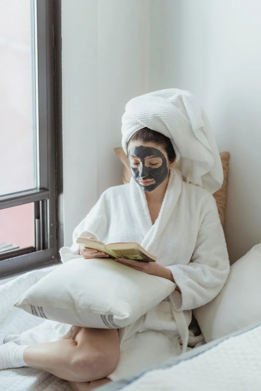 a person wearing a mask reading a book in bed