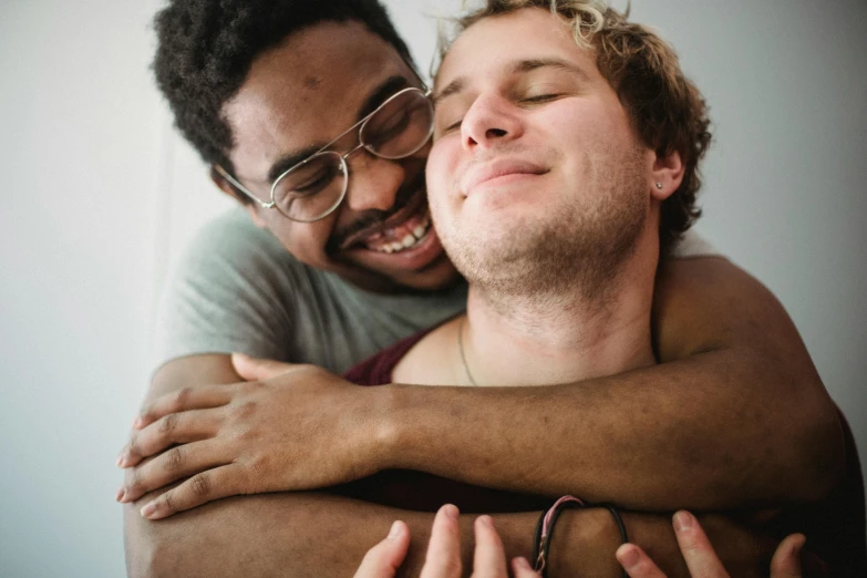 a smiling man hugging another man in his arms