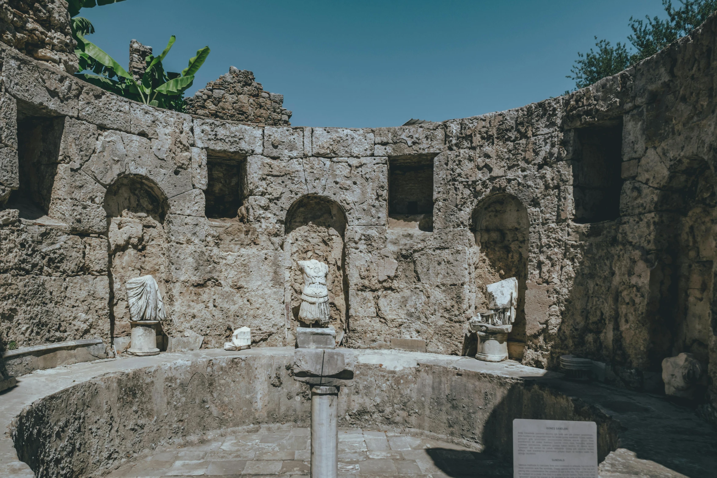 sculptures in a room with stone walls around it