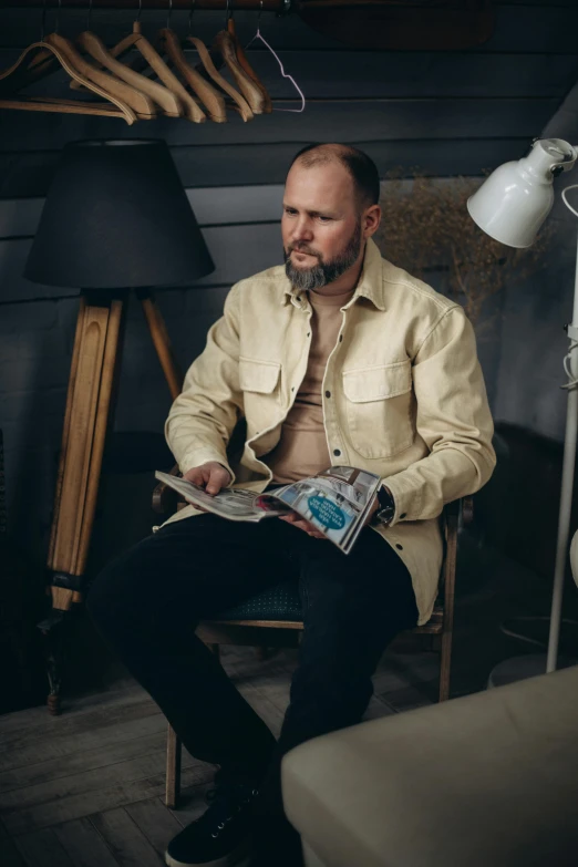 a man is sitting in a chair holding a newspaper