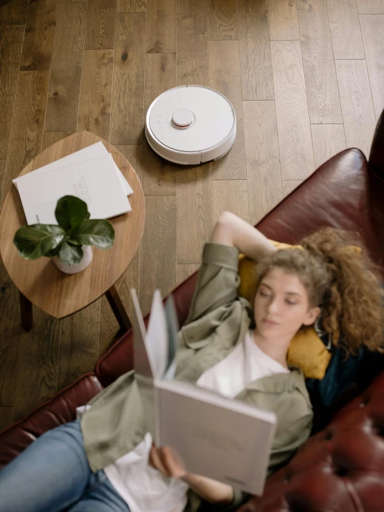 a woman lying on a leather couch reading a book