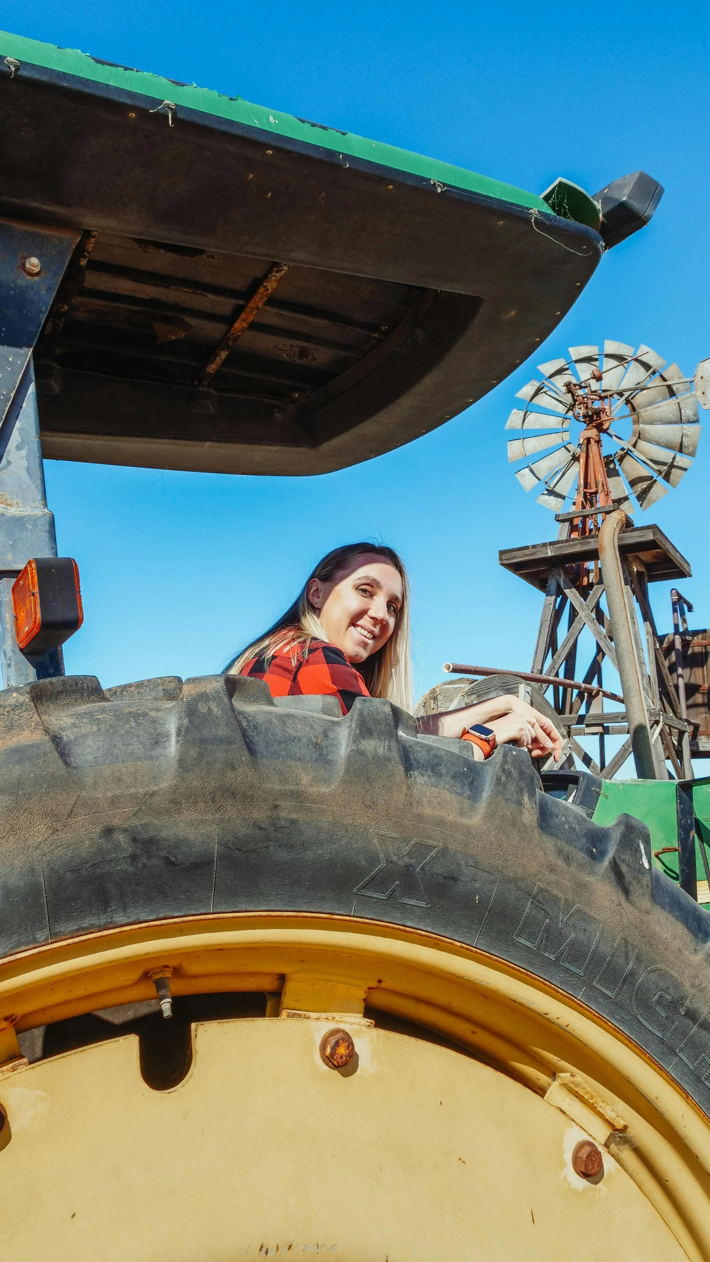 an odd picture of a woman smiling from inside the cab of a tractor