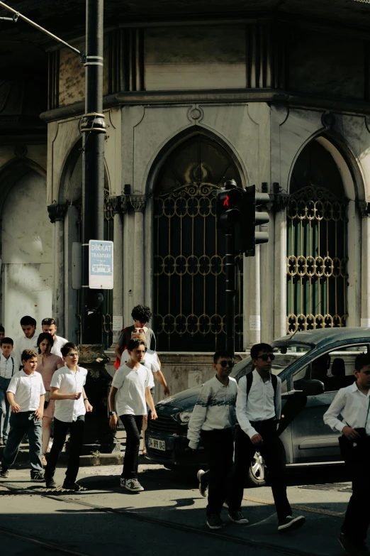 a group of s in school uniforms cross a street