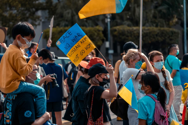 people standing outside holding flags and signs in each of their hands