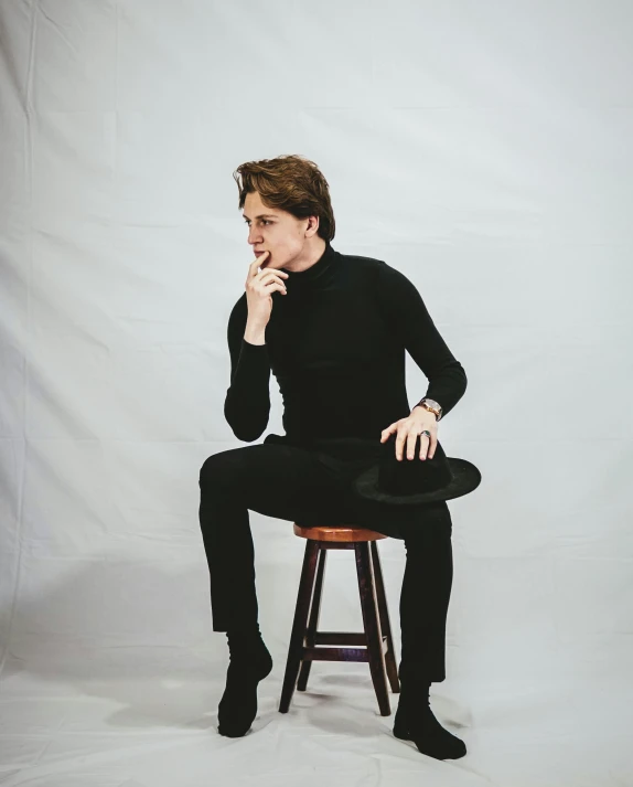 a man sitting on top of a stool holding a hat