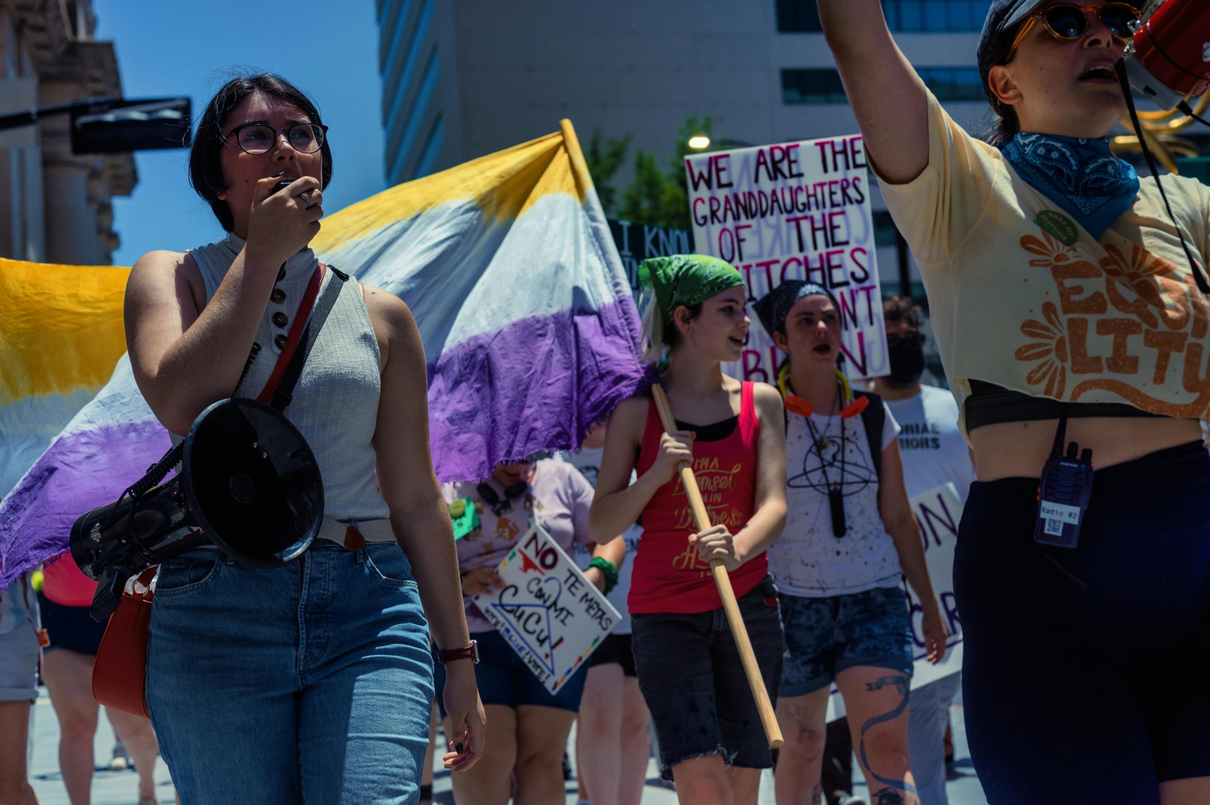 many people marching down the street holding flags and signs