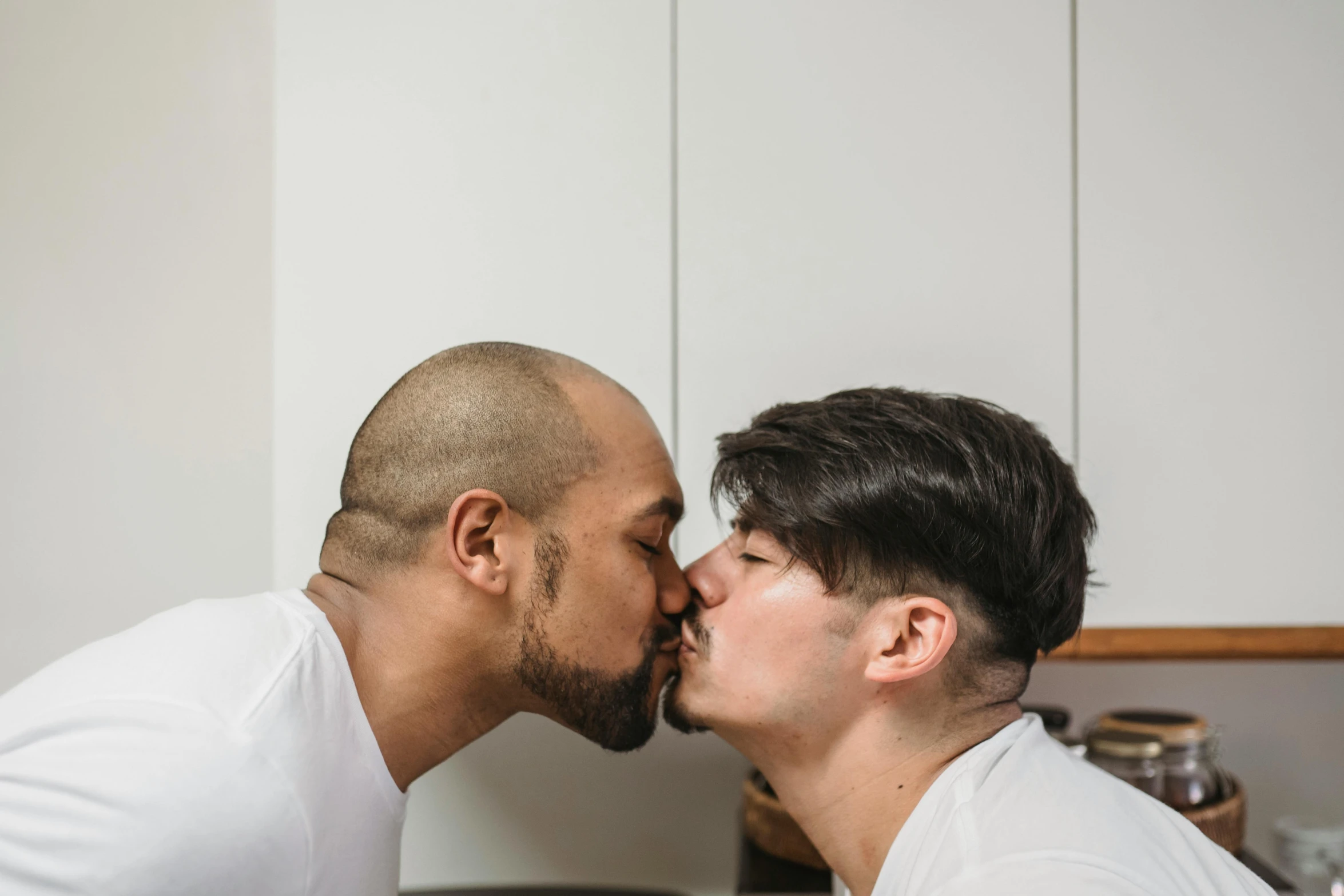 two men are kissing each other in the kitchen