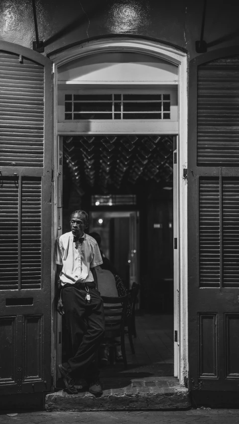 a man in a tie sits on a chair outside a door