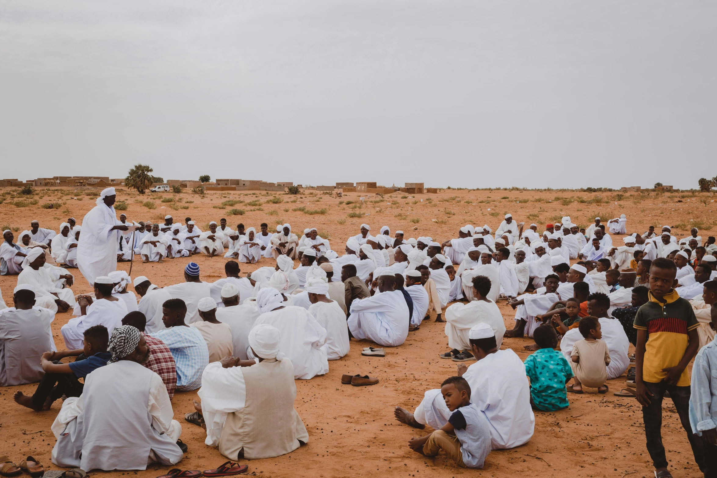 a group of people sitting on top of a sandy beach