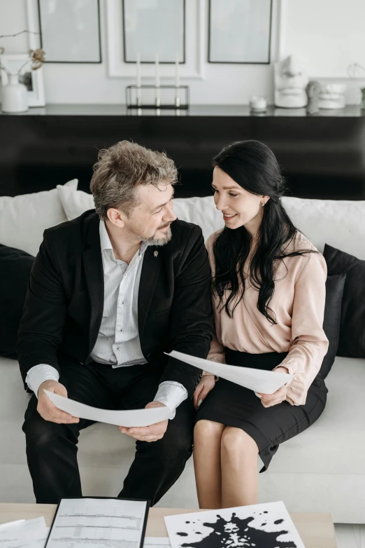 a man sitting next to a woman on top of a couch