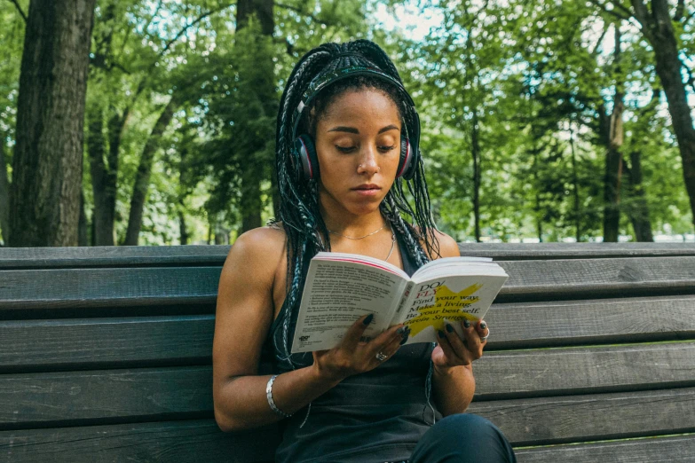 the woman is reading a book on a bench