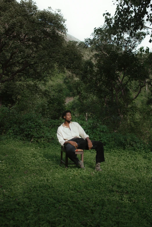 a man sitting on a chair next to a tree