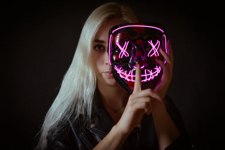 a blonde woman is holding a mask that has lights up