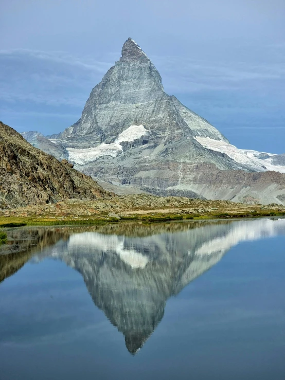 the mountain range is reflected in the still water