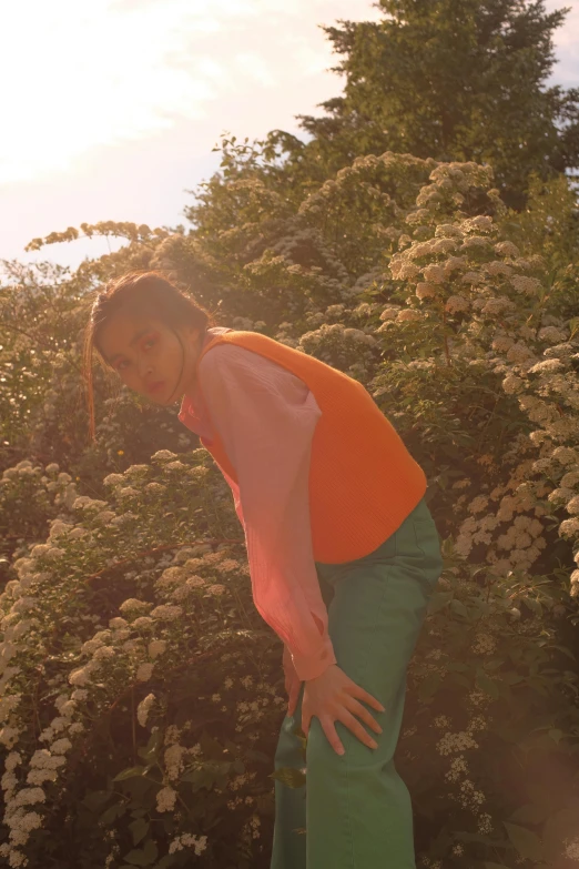 a woman standing on top of a snowboard next to bushes