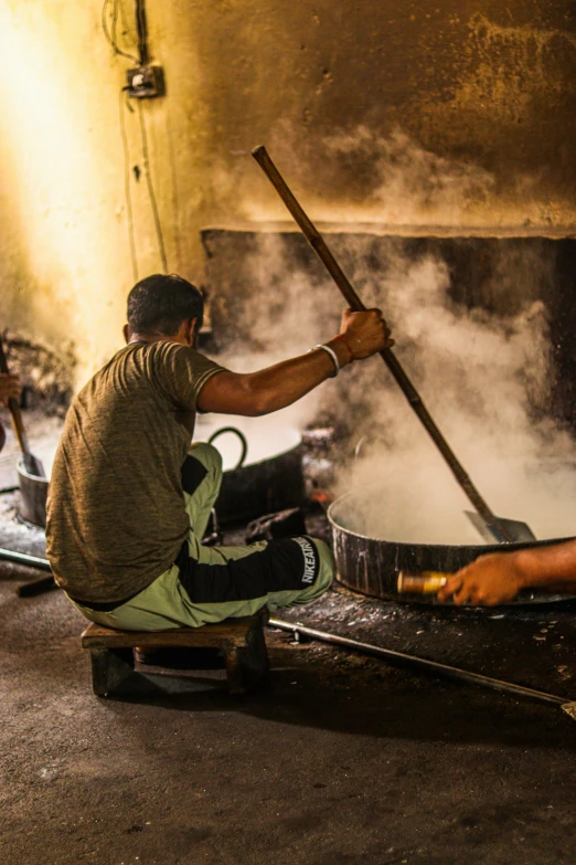 a man working in an ironing shop with a huge pot and a huge metal pan