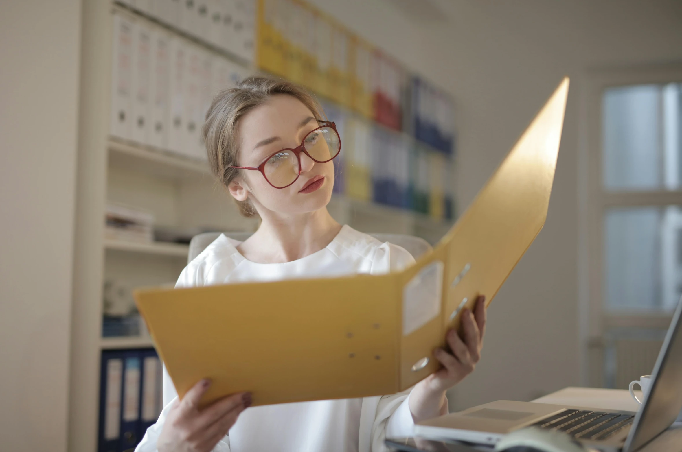 woman in glasses looking through binders on table