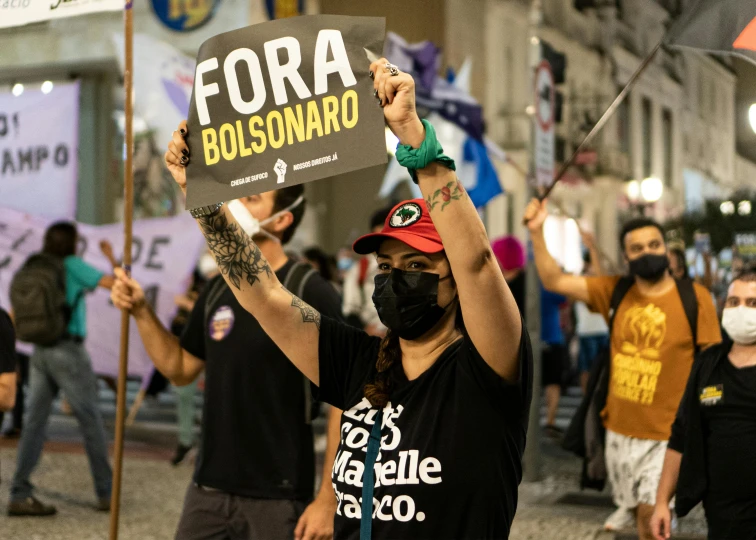 a woman holding a sign that says fora bolsunario