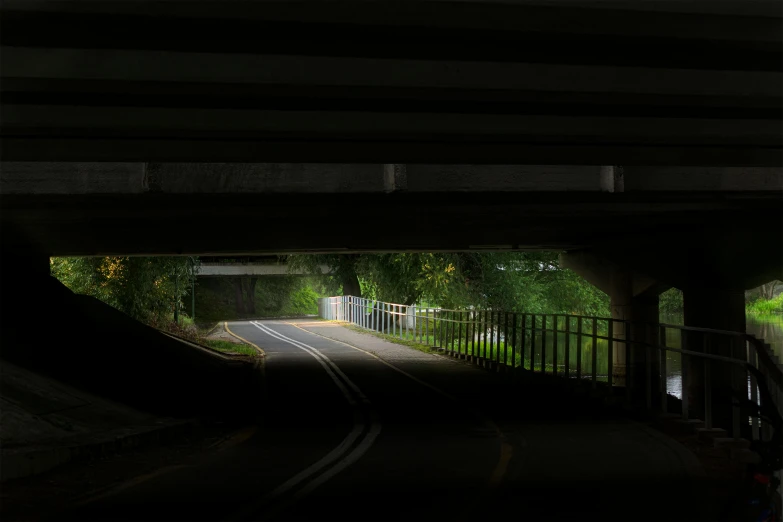 a couple people ride skateboards under a bridge