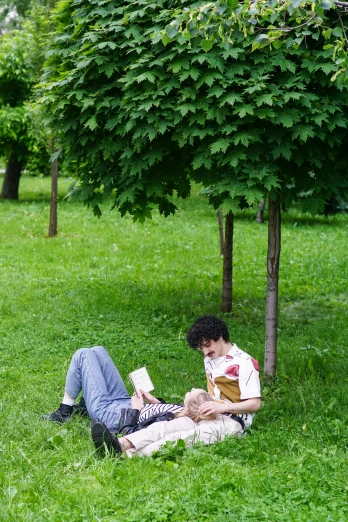 a person laying in the grass reading a book