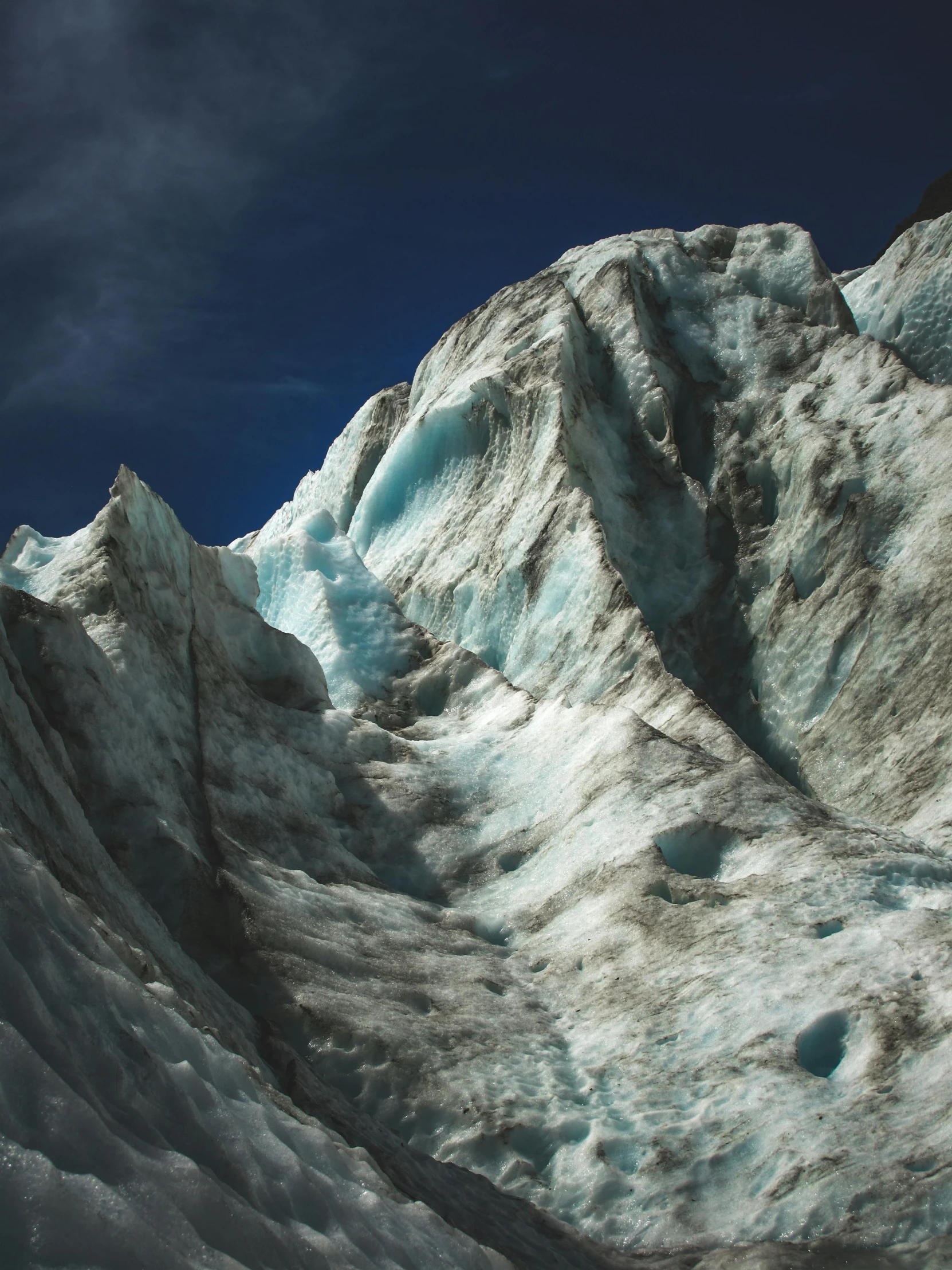 snow on a mountain, with the top partially covered by blue ice