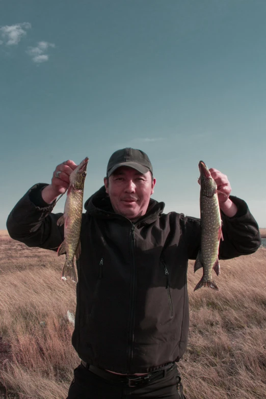 a man is standing in the open field with two fish